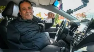 Chauffeur VTC à Angers tenant sa carte professionnelle officielle dans son véhicule